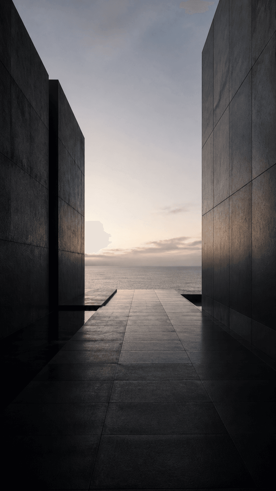 A quiet path between dark stone walls opening toward the sea